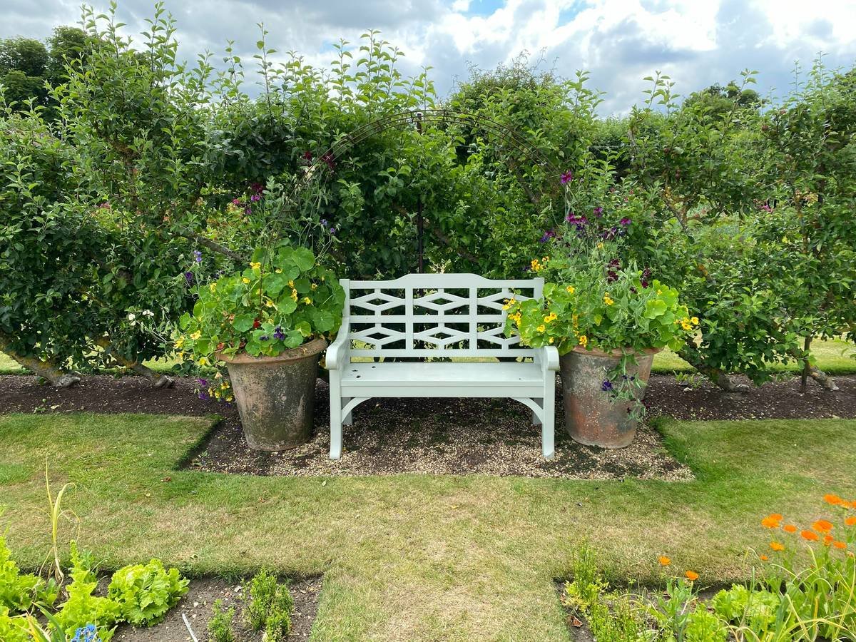 Infographic showing key zones around a garden bench: intimate (0-3 ft), transitional (3-8 ft), and backdrop (8+ ft) with recommended decor elements for each